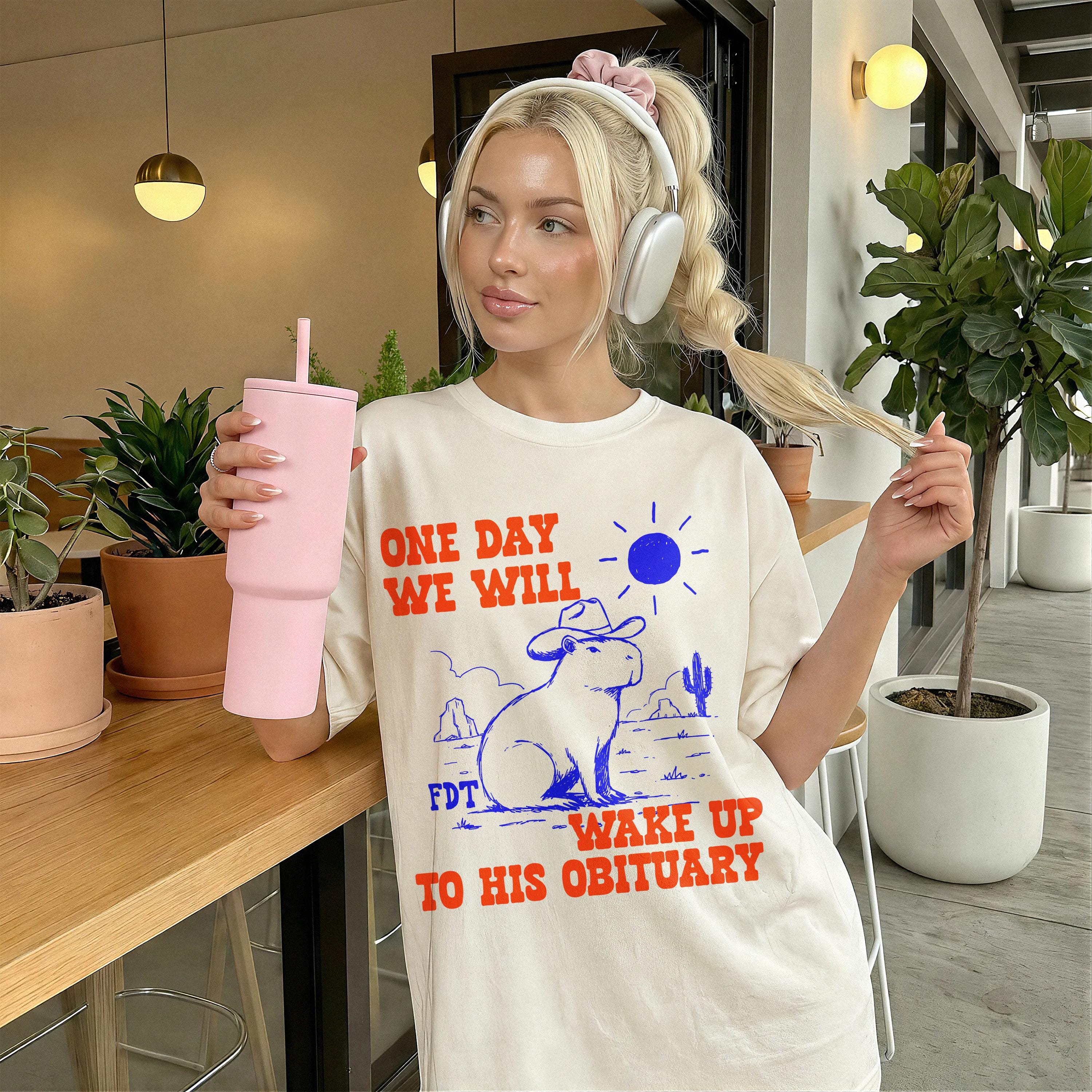 Cream t-shirt with graphic: "ONE DAY WE WILL WAKE UP TO HIS OBITUARY."