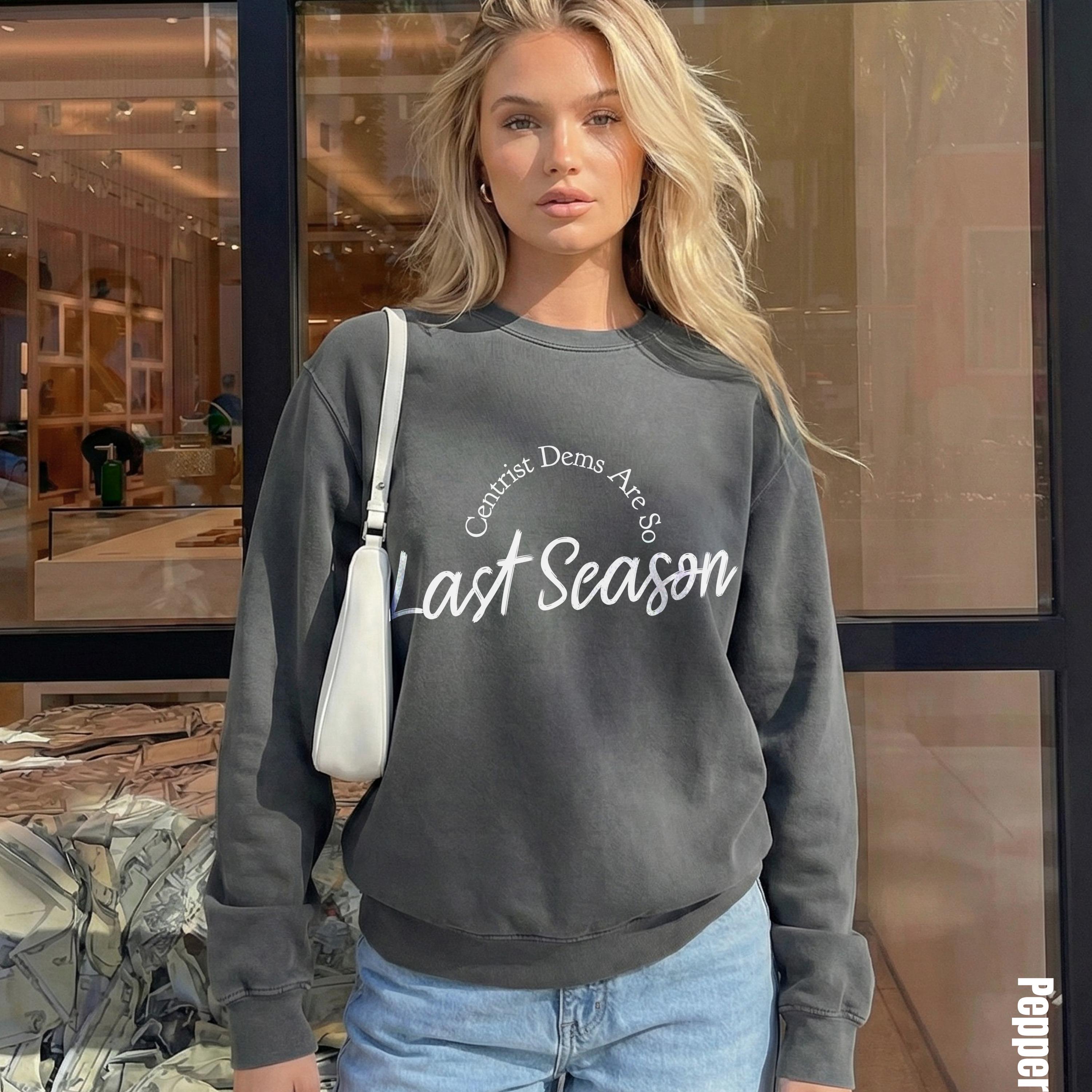 Woman wearing gray sweatshirt with text "Centrist Dems Are So Last Season" and white crossbody bag.