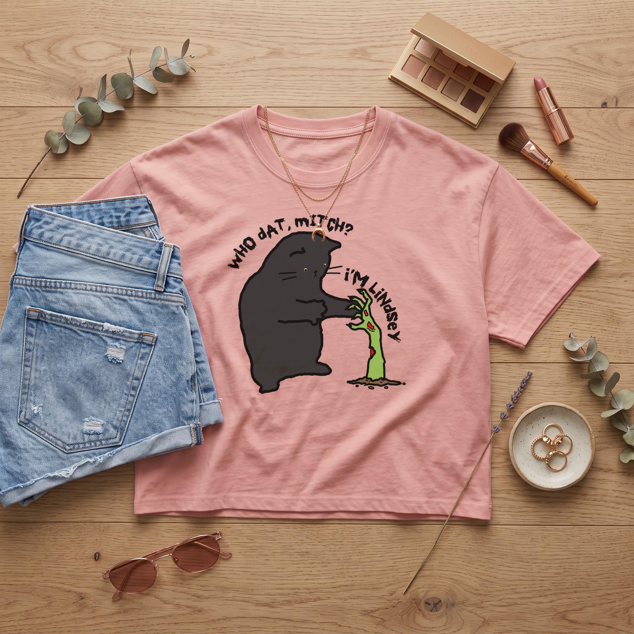 Pink t-shirt featuring a black cat and zombie hand graphic with text.
