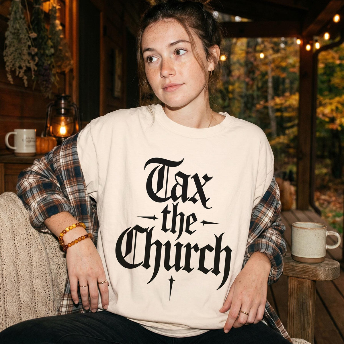 Cream t-shirt with black gothic text reading "Tax the Church" on a woman.