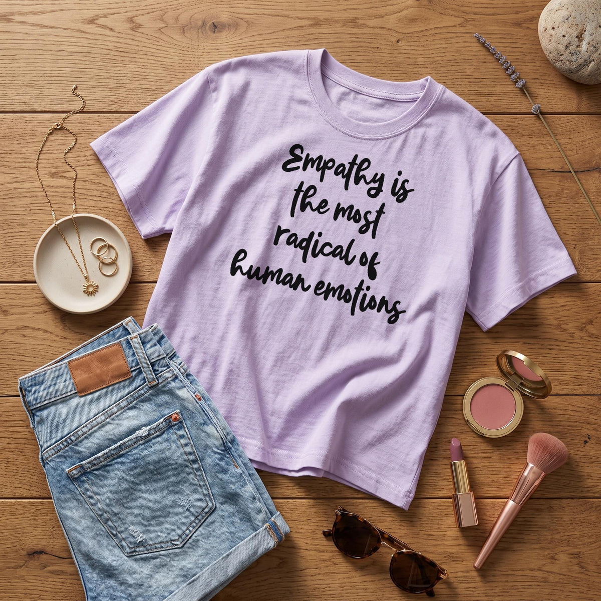 Lavender t-shirt with "Empathy is the most radical of human emotions" text, denim shorts, and jewelry.