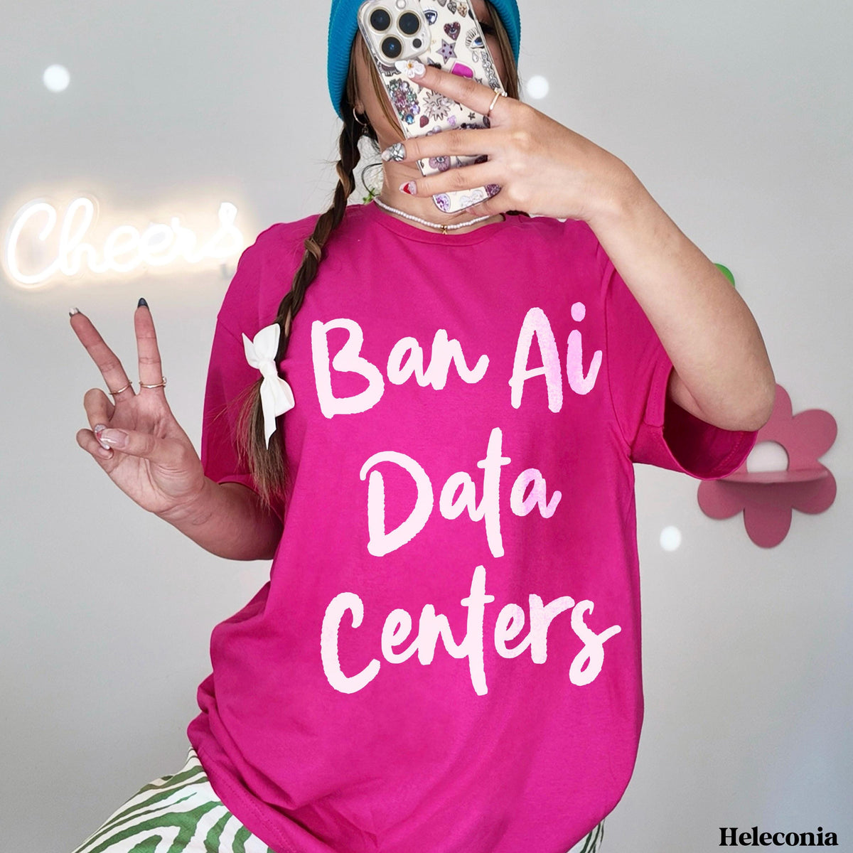 Pink t-shirt with white text "Ban Ai Data Centers," woman posing with phone.