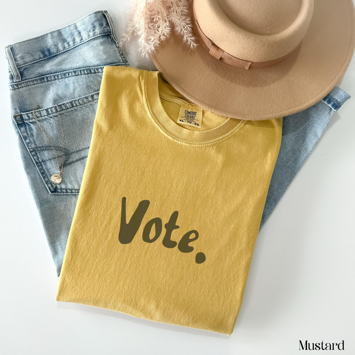 Mustard t-shirt with "Vote." graphic, jeans, and hat.