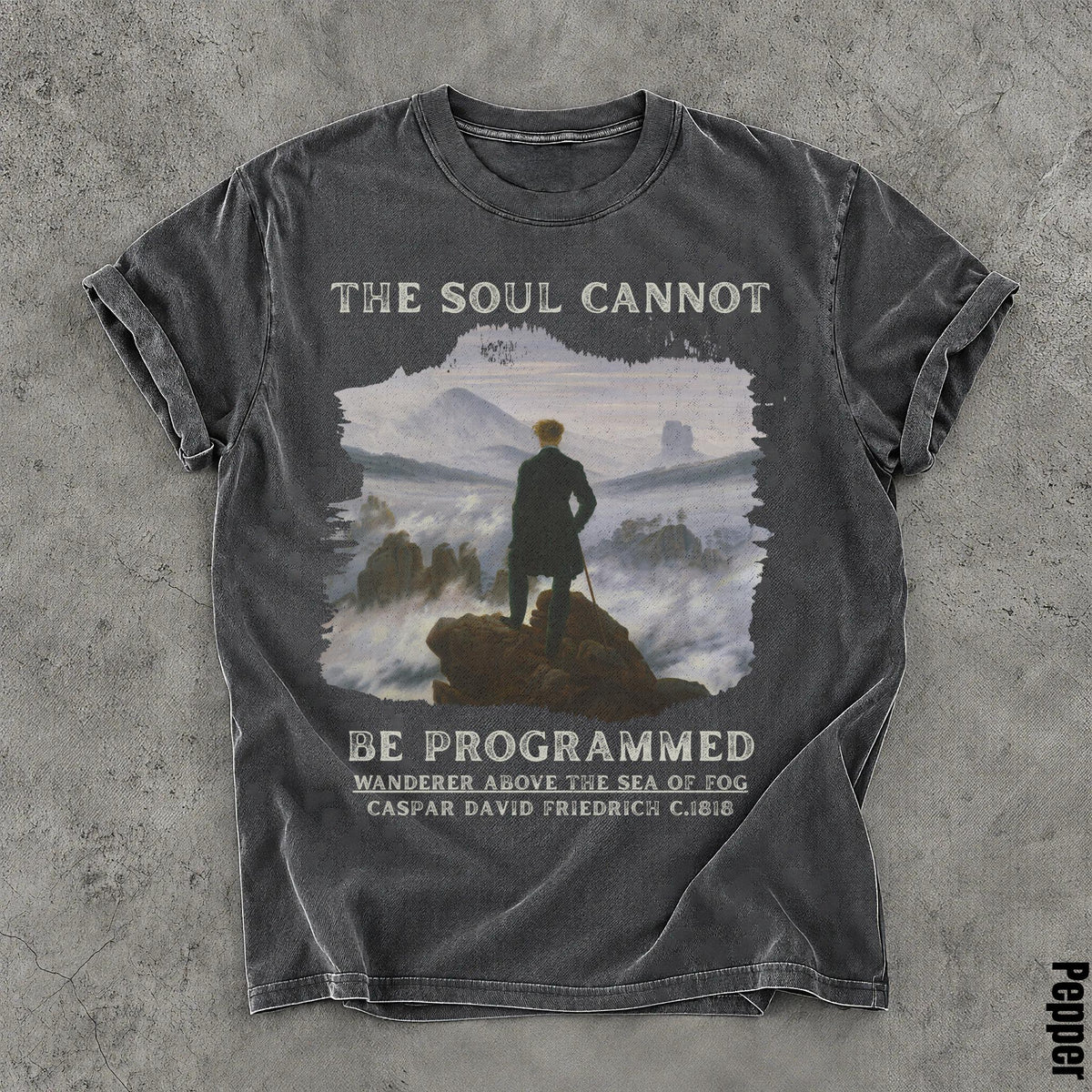T-shirt graphic: man on rock, foggy landscape, "The soul cannot be programmed" and artwork details.