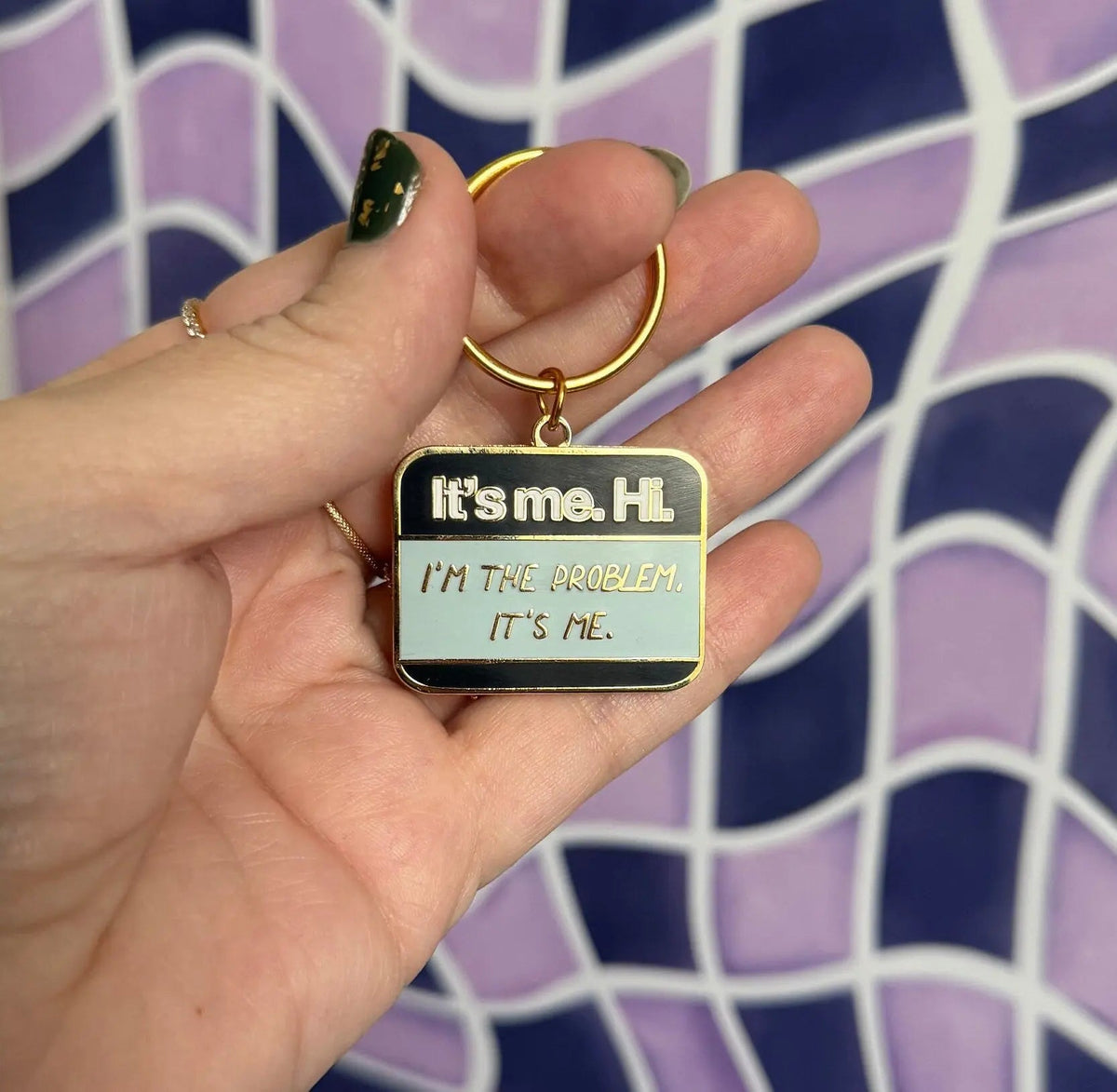 It’s me Hi I’m the problem It’s me enamel keychain flat lay — hand lettered name tag keyring on a split ring by indie artist MangoIllustrated