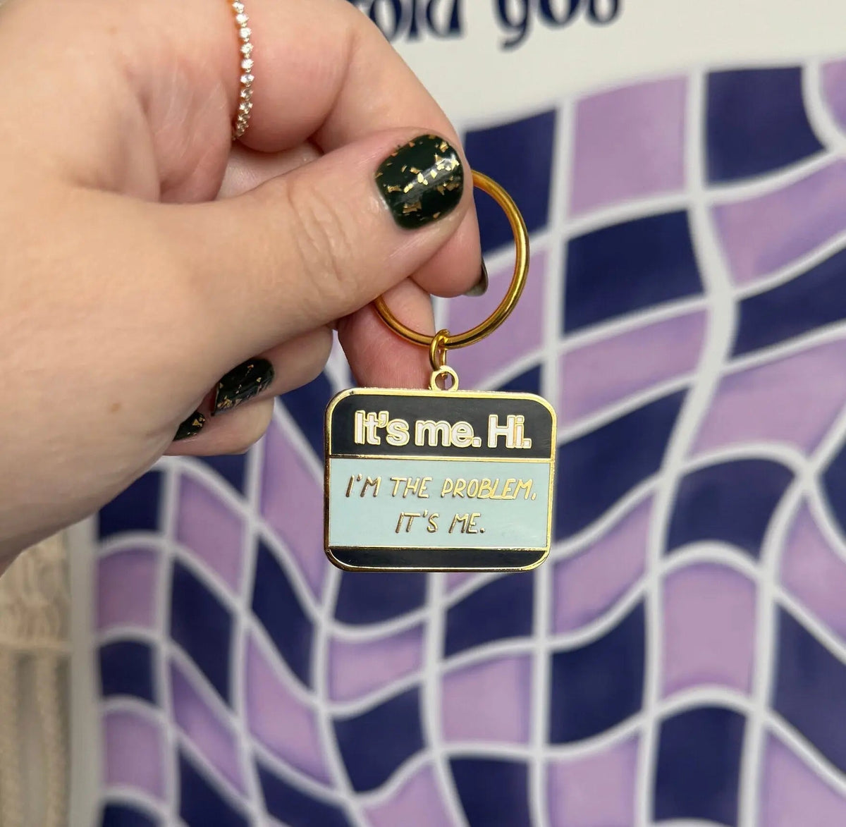 It’s me Hi I’m the problem It’s me enamel keychain back detail — reverse side of the hard enamel keyring by indie artist MangoIllustrated