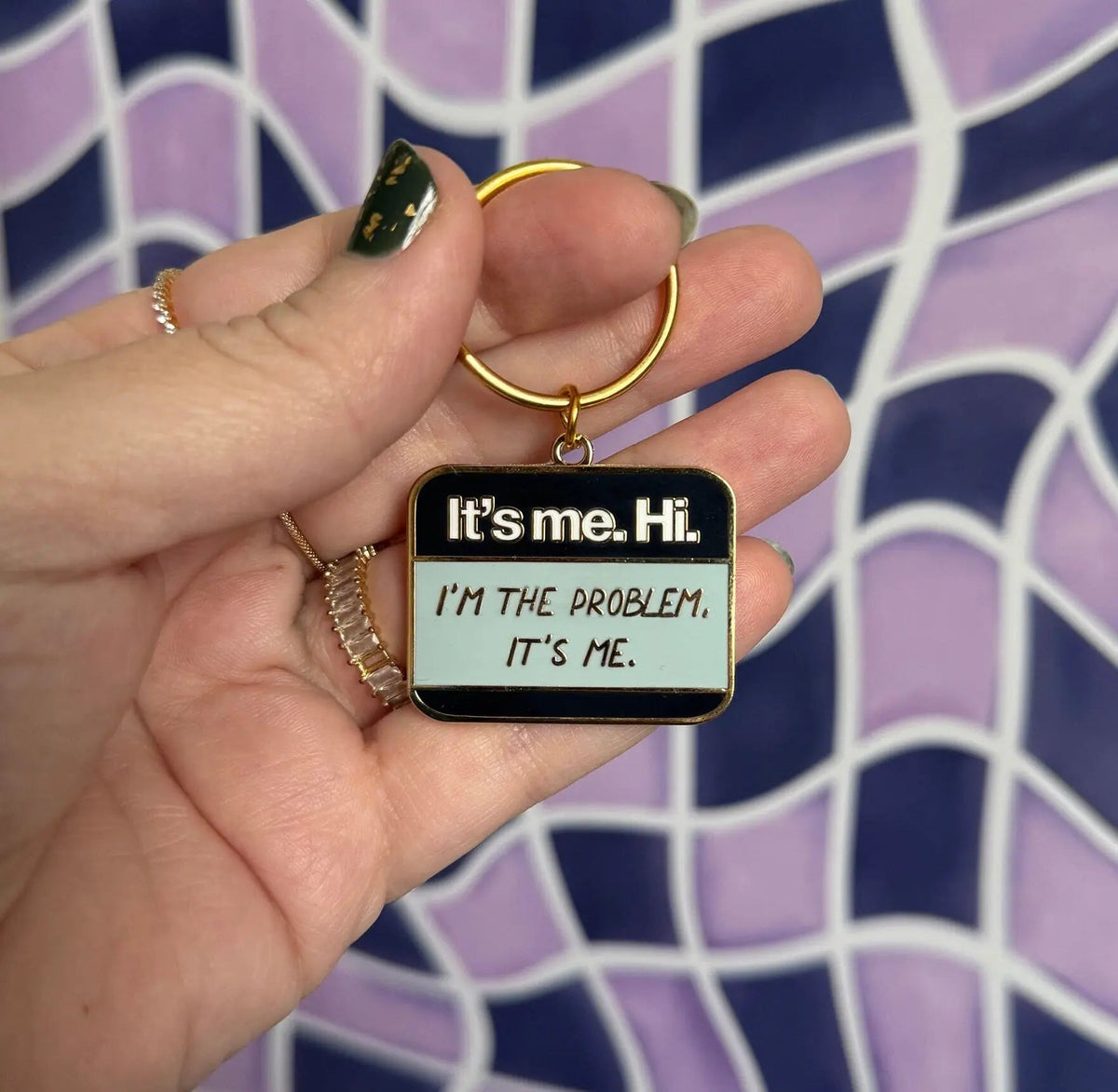 It’s me Hi I’m the problem It’s me enamel keychain — Hello name tag shaped hard enamel keychain in navy, light blue and white with gold lettering, 1.5 in, by MangoIllustrated