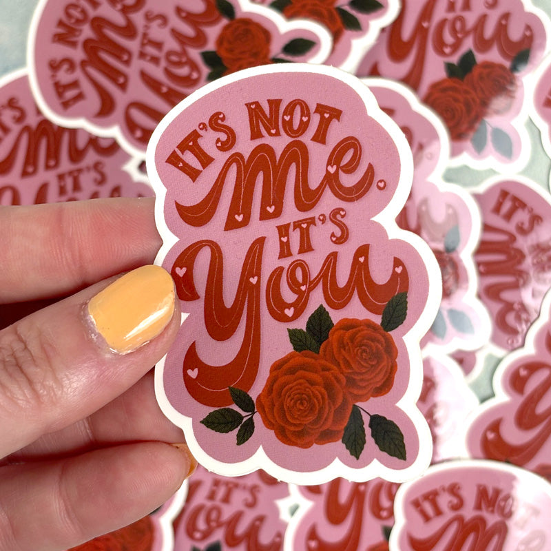 hand holding A pink sticker with the text &