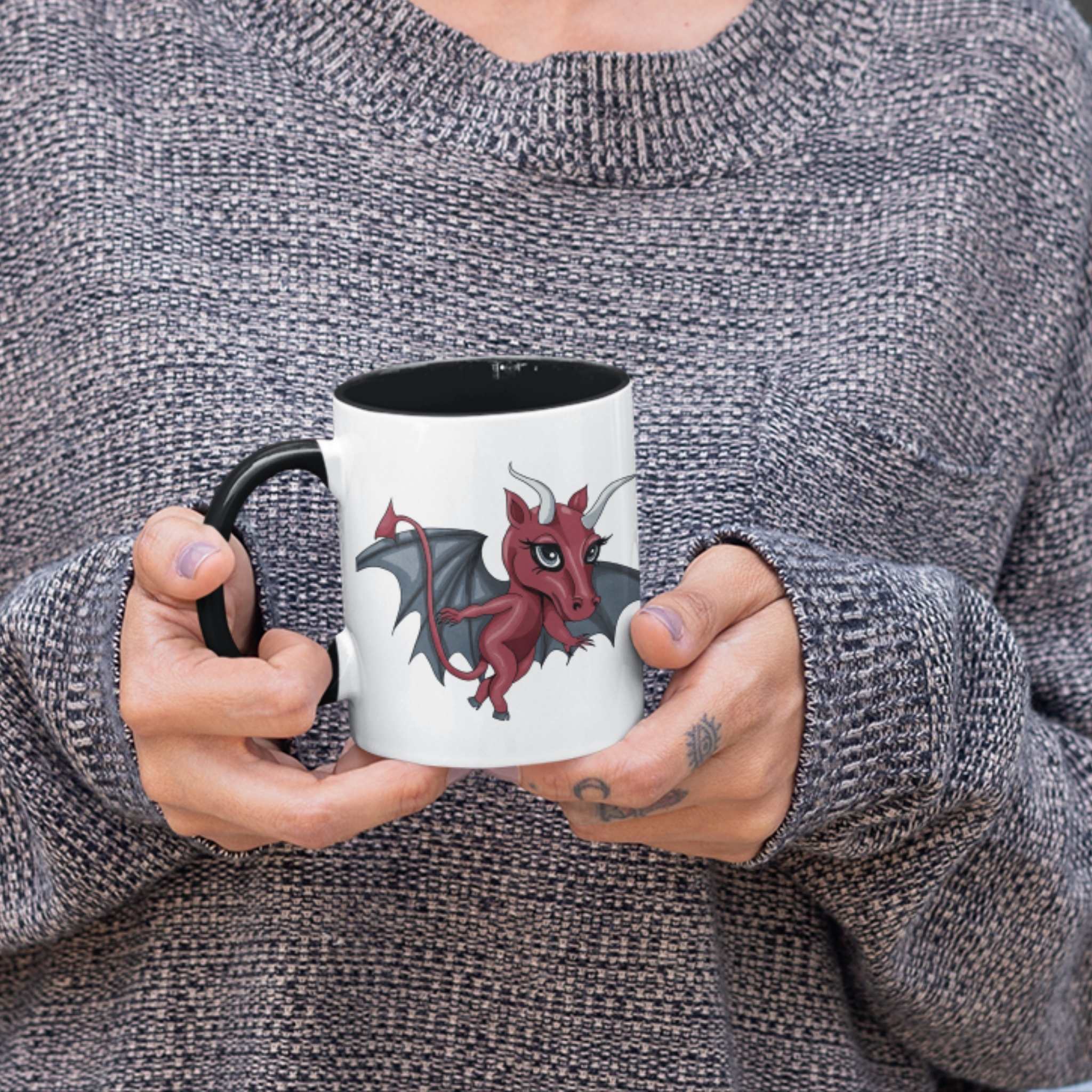 Person in a gray sweater holding the cute Jersey Devil cryptid coffee mug