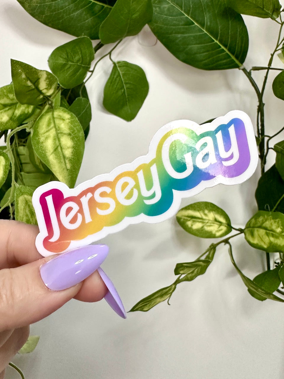 the die cut sticker reads "jersey gay" in white lettering with a rainbow offset.