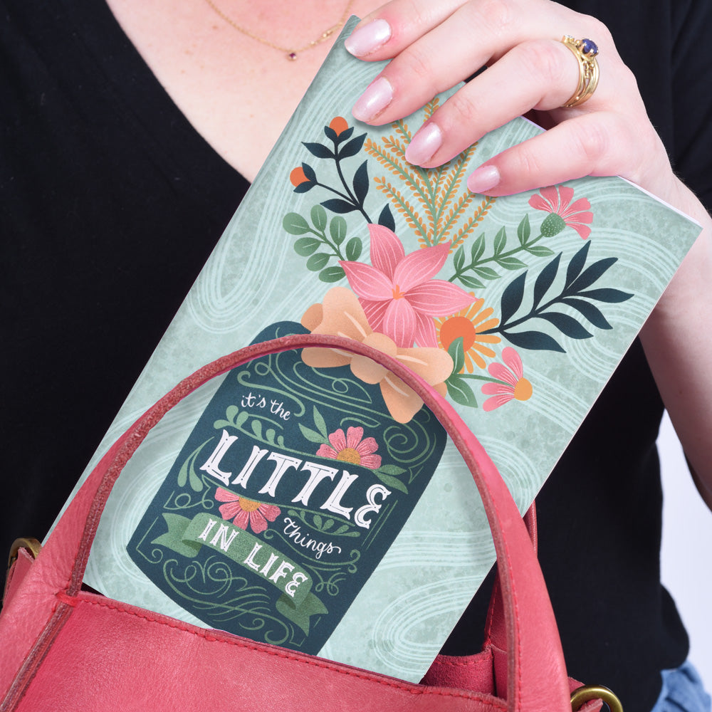 hands putting a flatlay notebook with green flower vase that says "it&