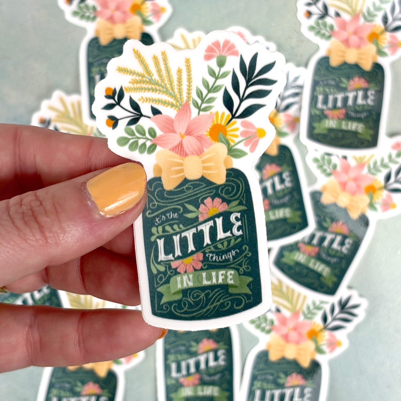 hand holding a sticker of a flower vase with lettering "it&