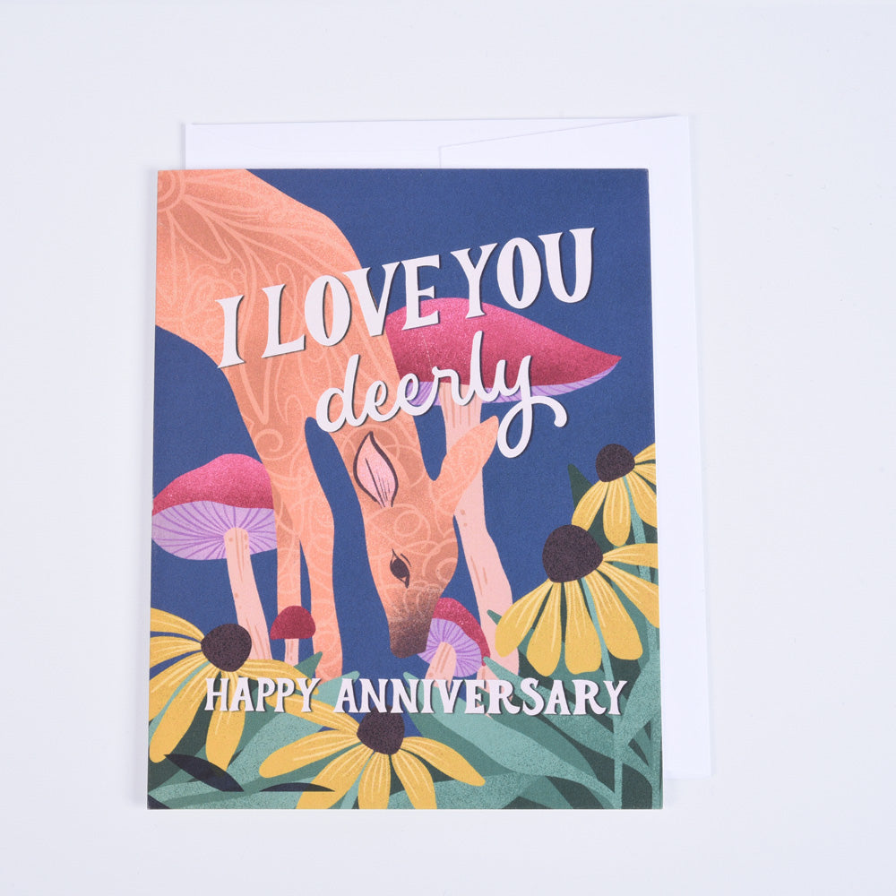 A folded greeting card with a colorful illustration of a deer and mushrooms, with the text &