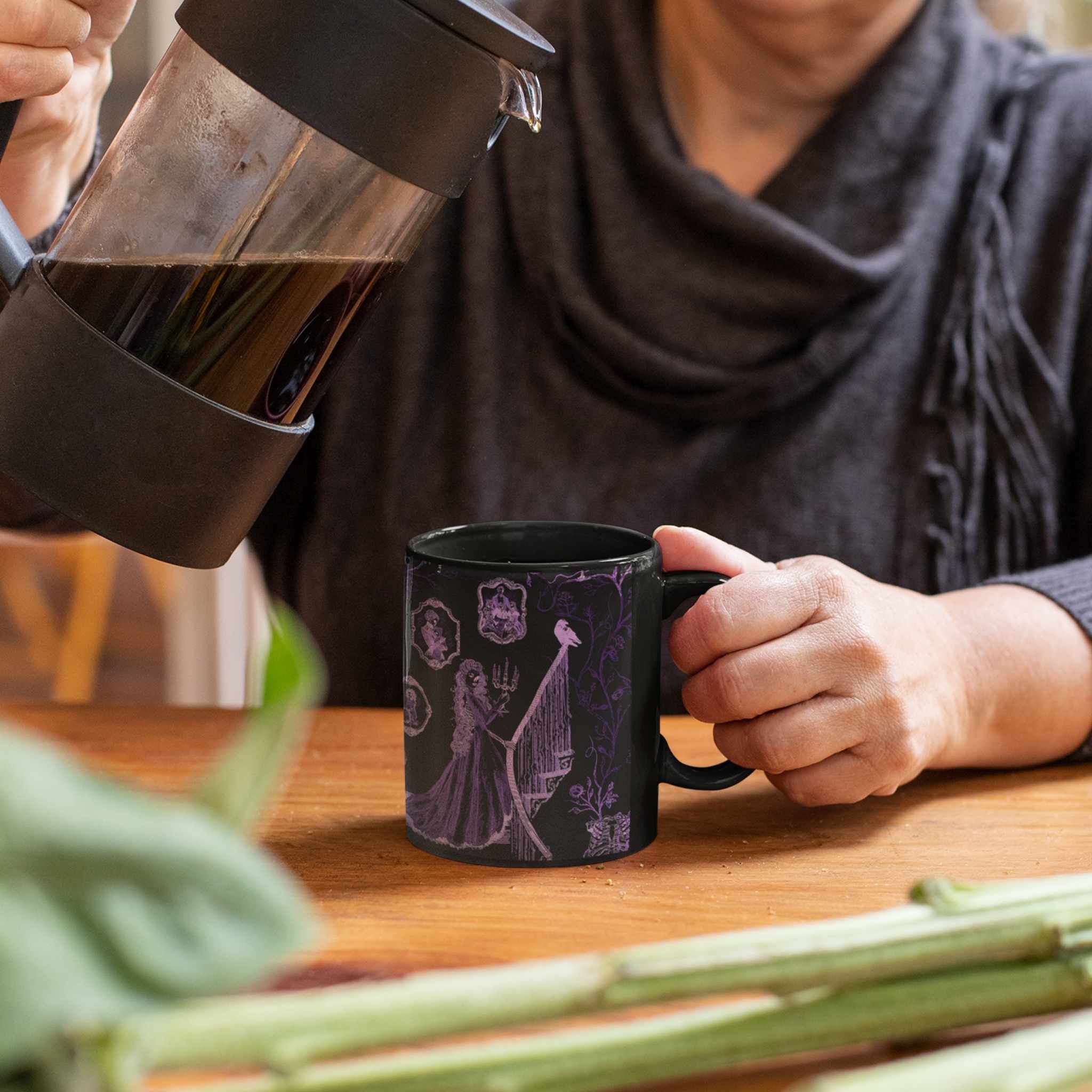 Coffee being poured from a French press into a purple zombie toile mug at a wooden kitchen table
