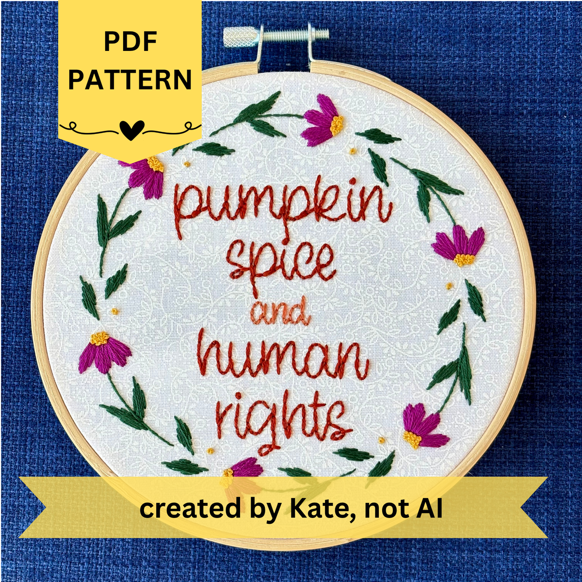 PDF pattern. Created by Kate, not AI. "Pumpkin spice and human rights". Handwriting font text hand embroidered in two shades of medium orange. Surrounded by a floral wreath of bright pink asters with yellow centers and green leaves and stems. Framed in light wood embroidery hoop and displayed as wall art.