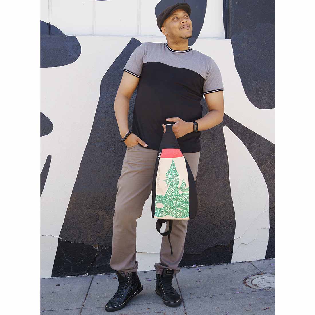 cool guy holding sling style sustainable backpak - serpent design