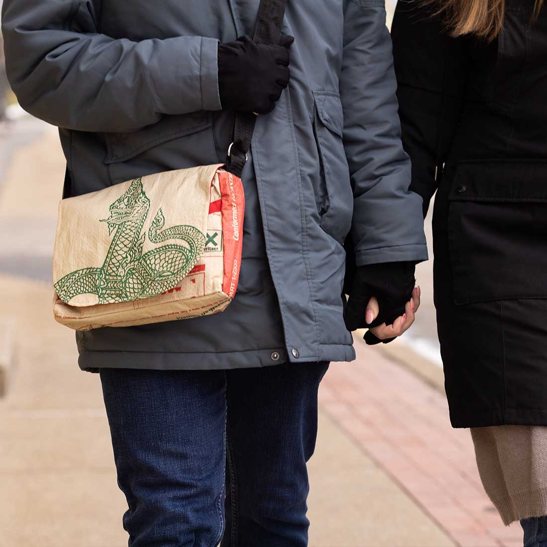 man wearing a small recycled messenger bag with serpent design