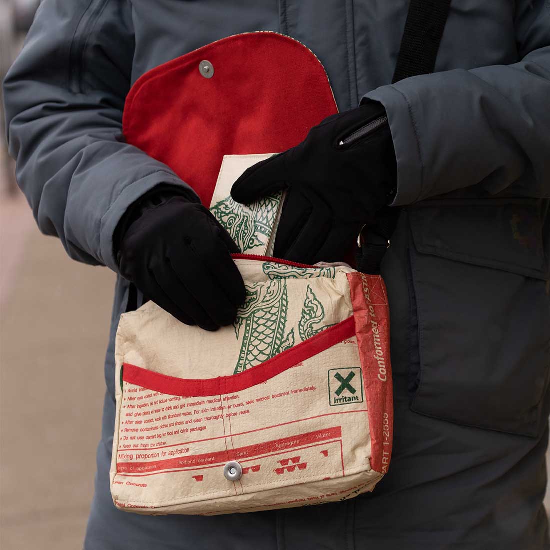 man reaching into small recycled messenger bag