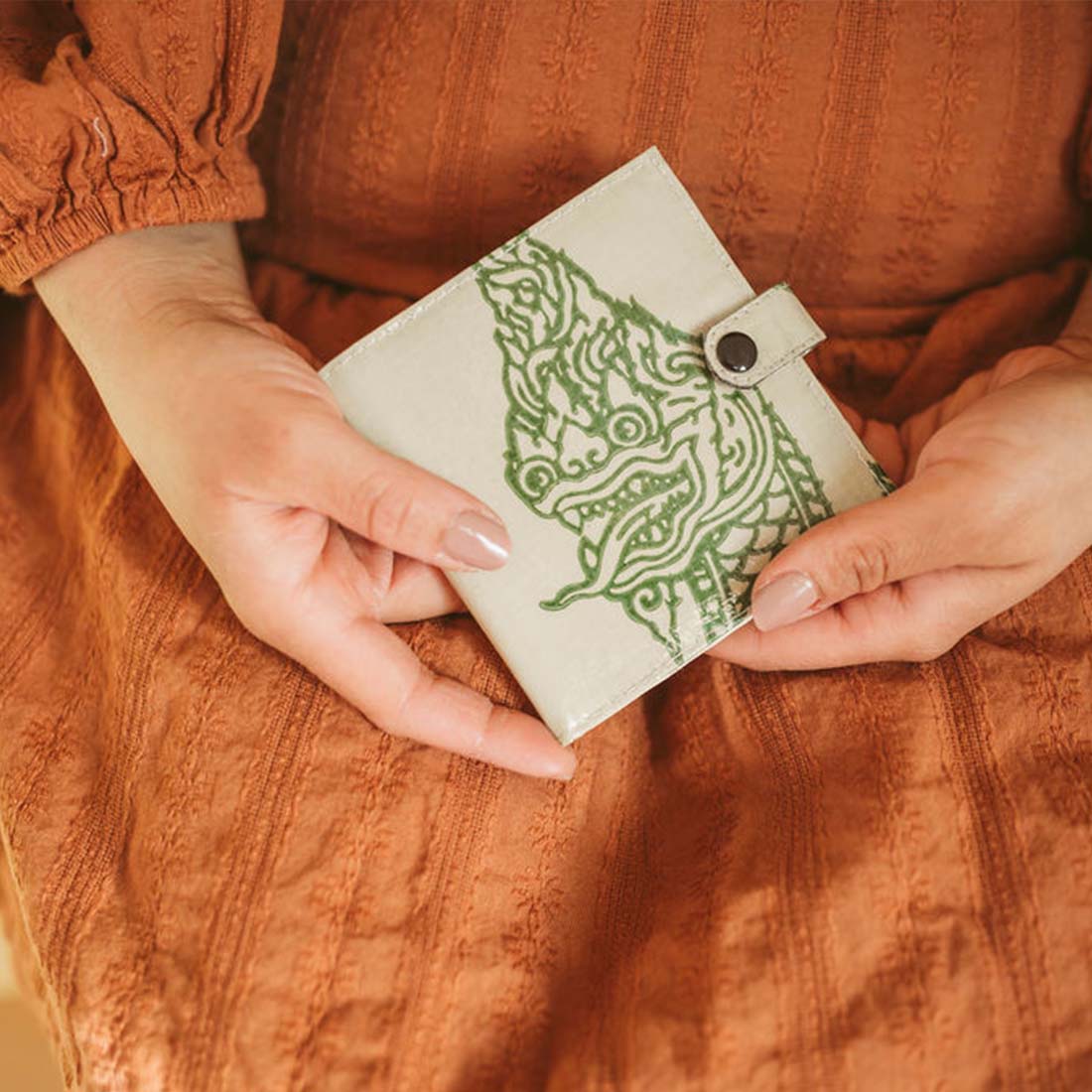 woman holding a small square upcycled wallet with a serpent design