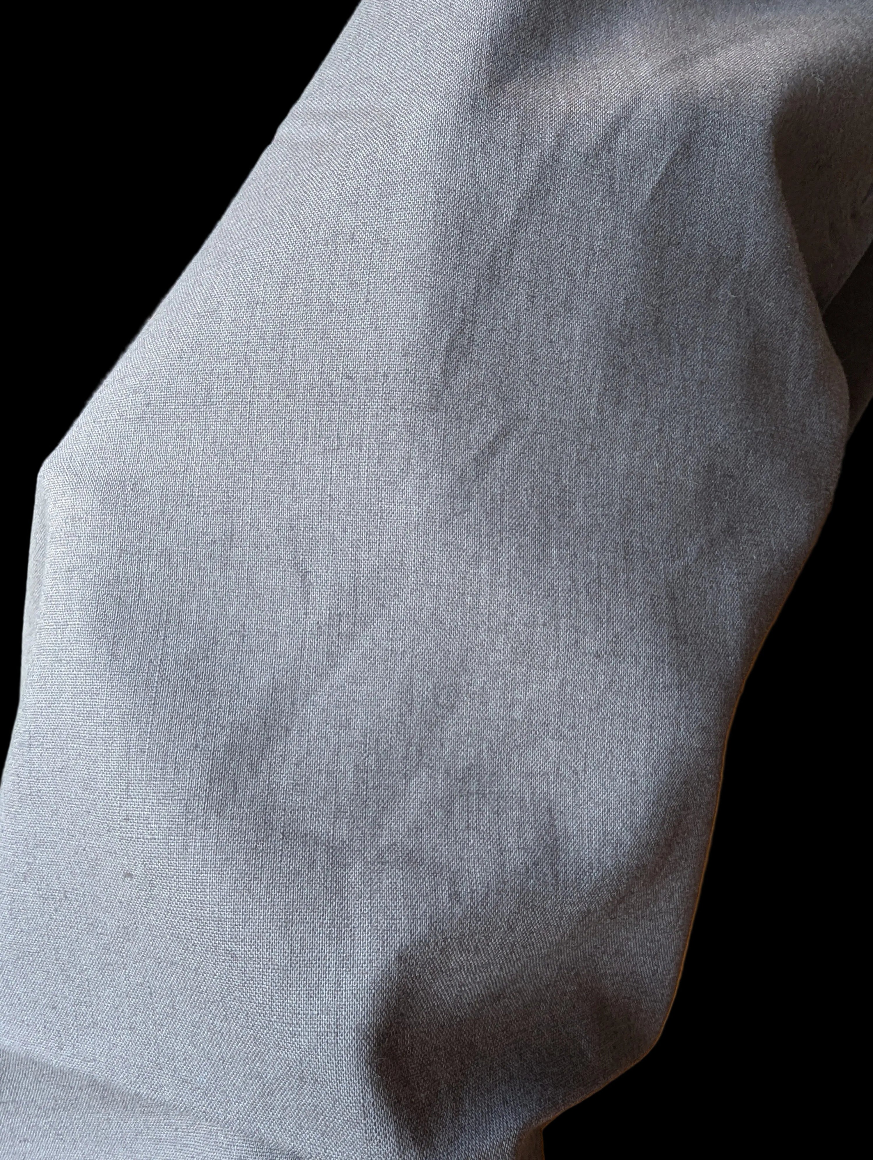 Hand underneath gray linen fabric to show opacity.