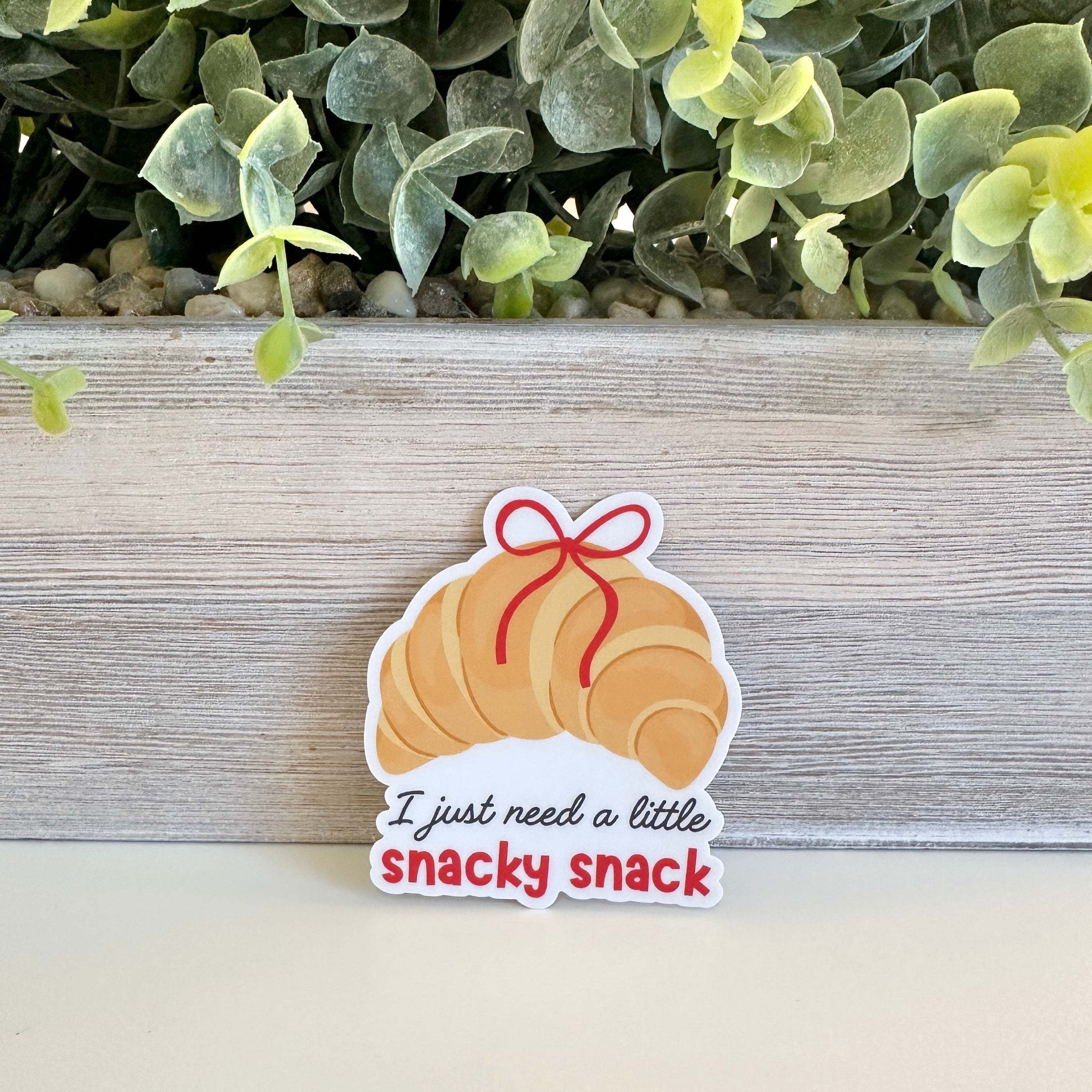 Sticker of a croissant with a bow and text &