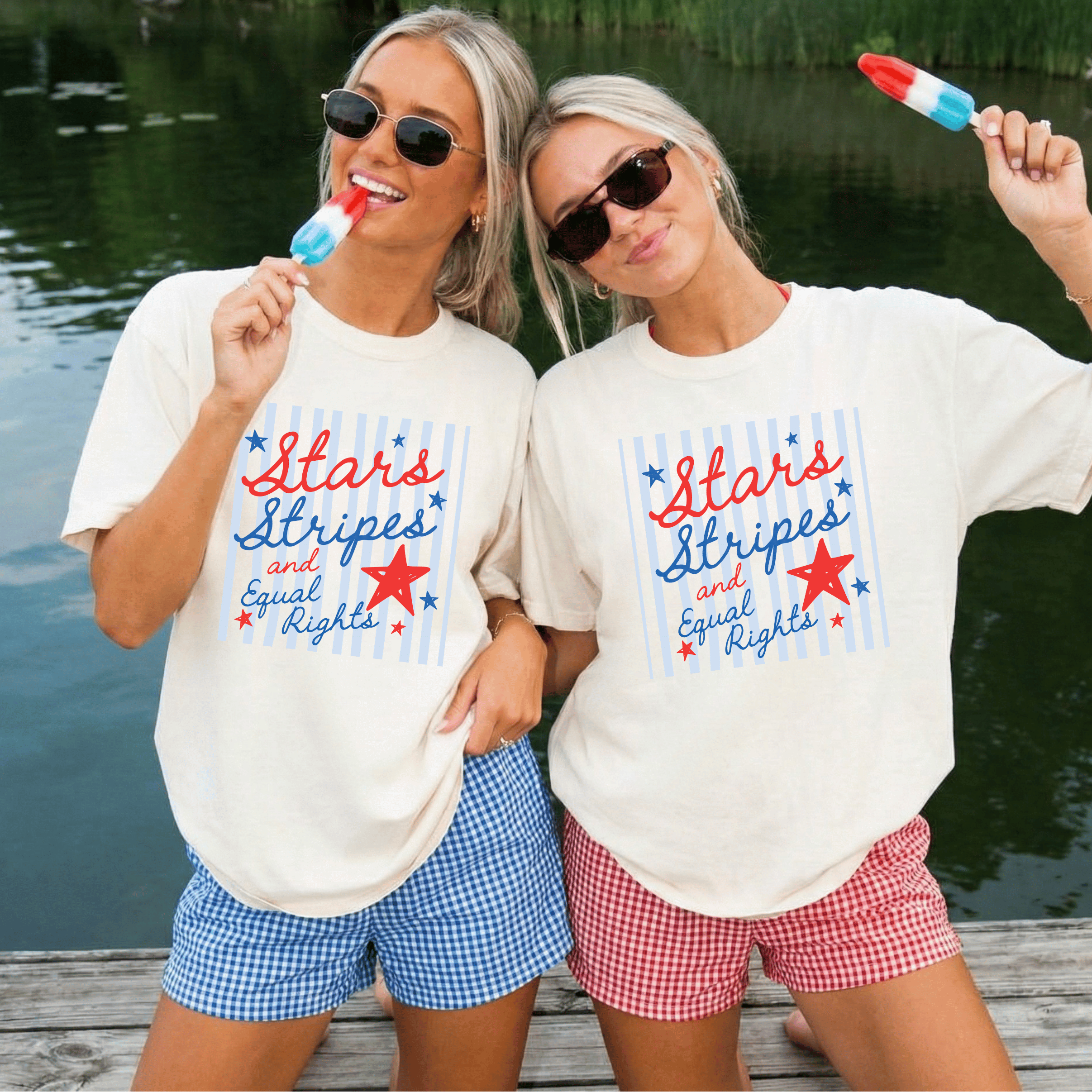 Two women wearing matching t-shirts that read stars stripes and equal rights with a patriotic design by a lake.