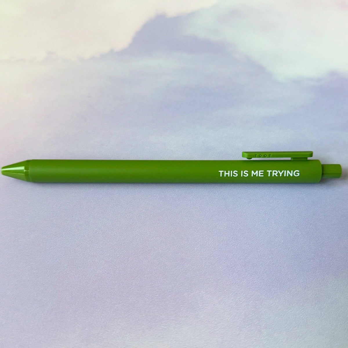This is Me Trying jotter gel pen flat lay — olive barrel folklore era desk pen by indie artist MangoIllustrated