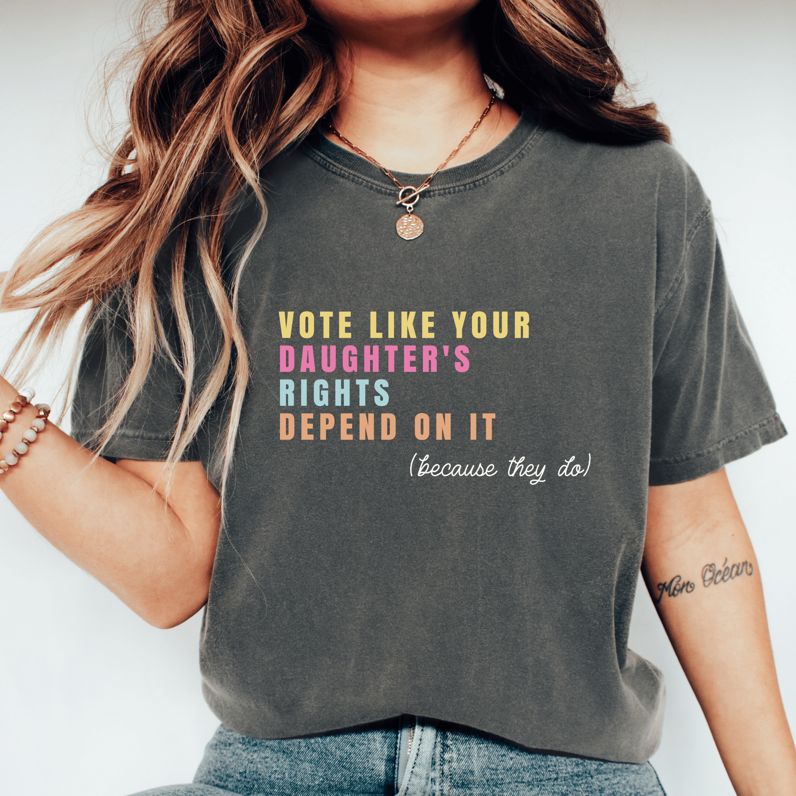 A woman wearing a dark gray graphic t-shirt with the text &