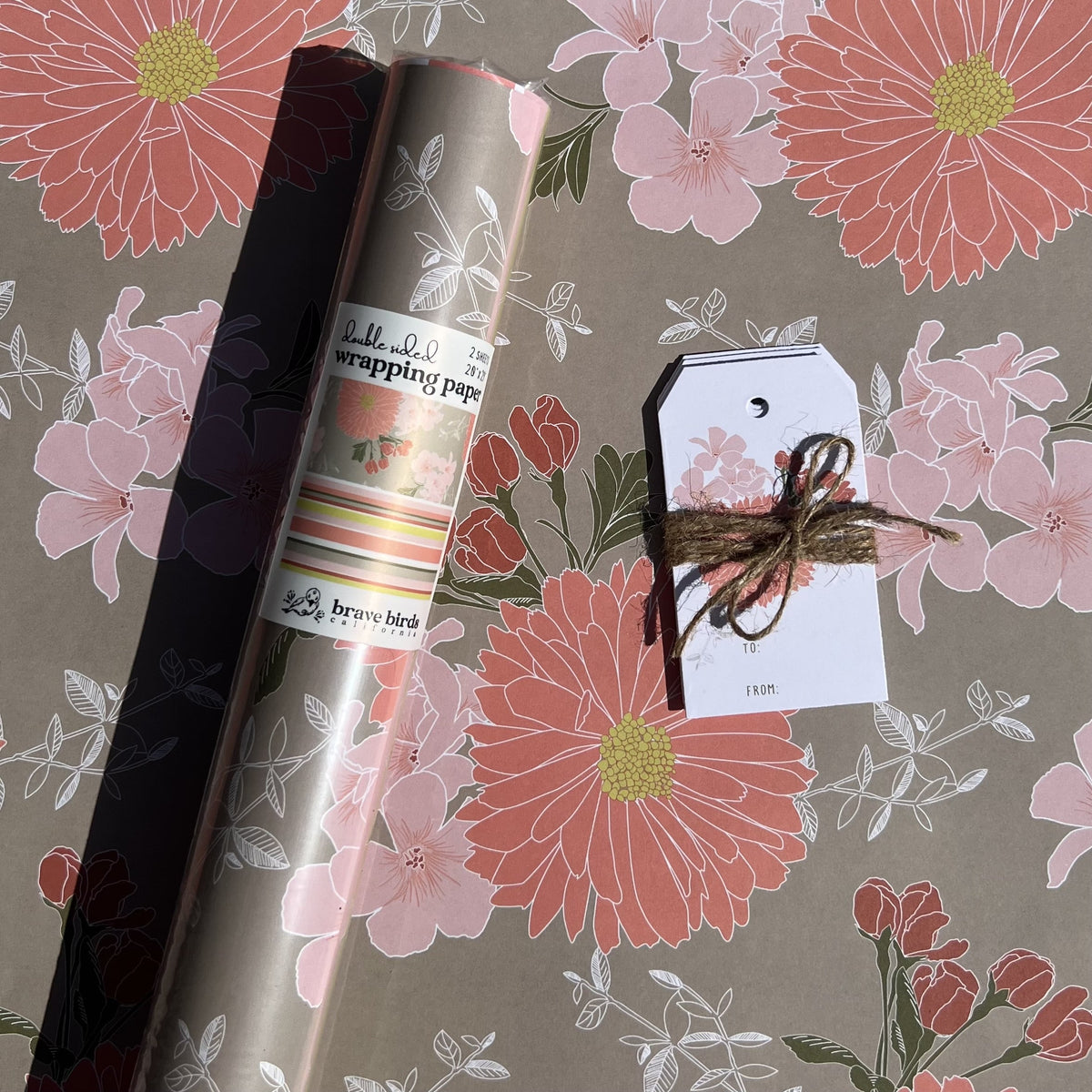 Packaged roll of wrapping paper sitting on a flat sheet of the paper showing the full pattern, shown with coordinating gift tags