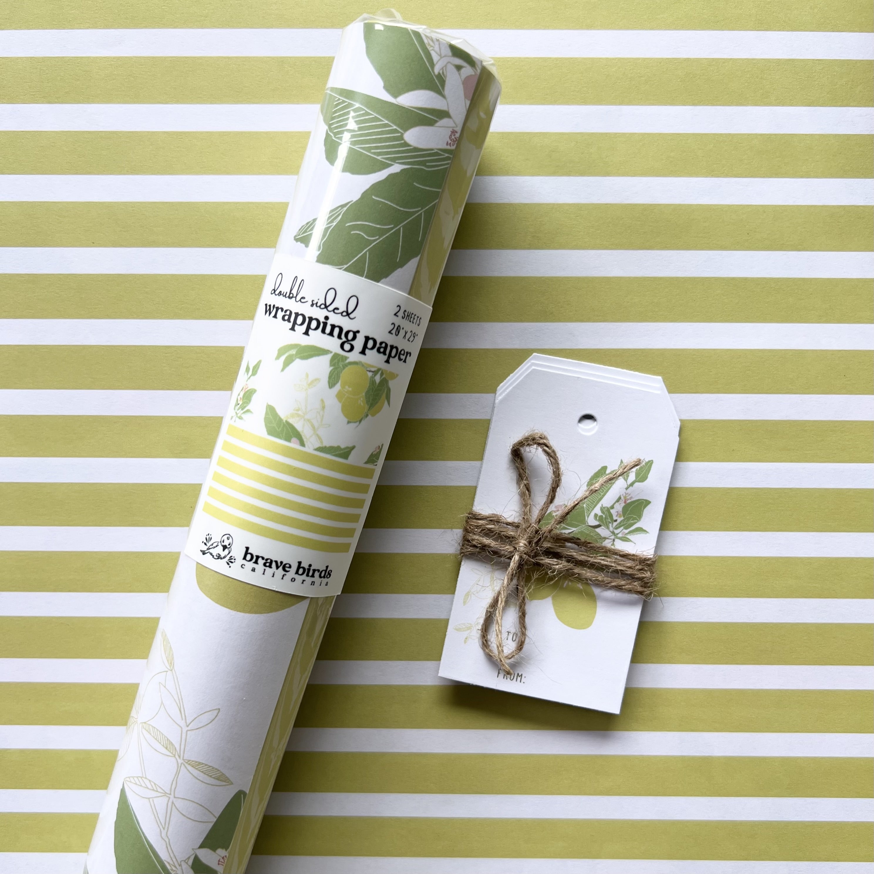 Packaged roll of wrapping paper sitting on a flat sheet of the paper showing the full pattern, shown with coordinating gift tags