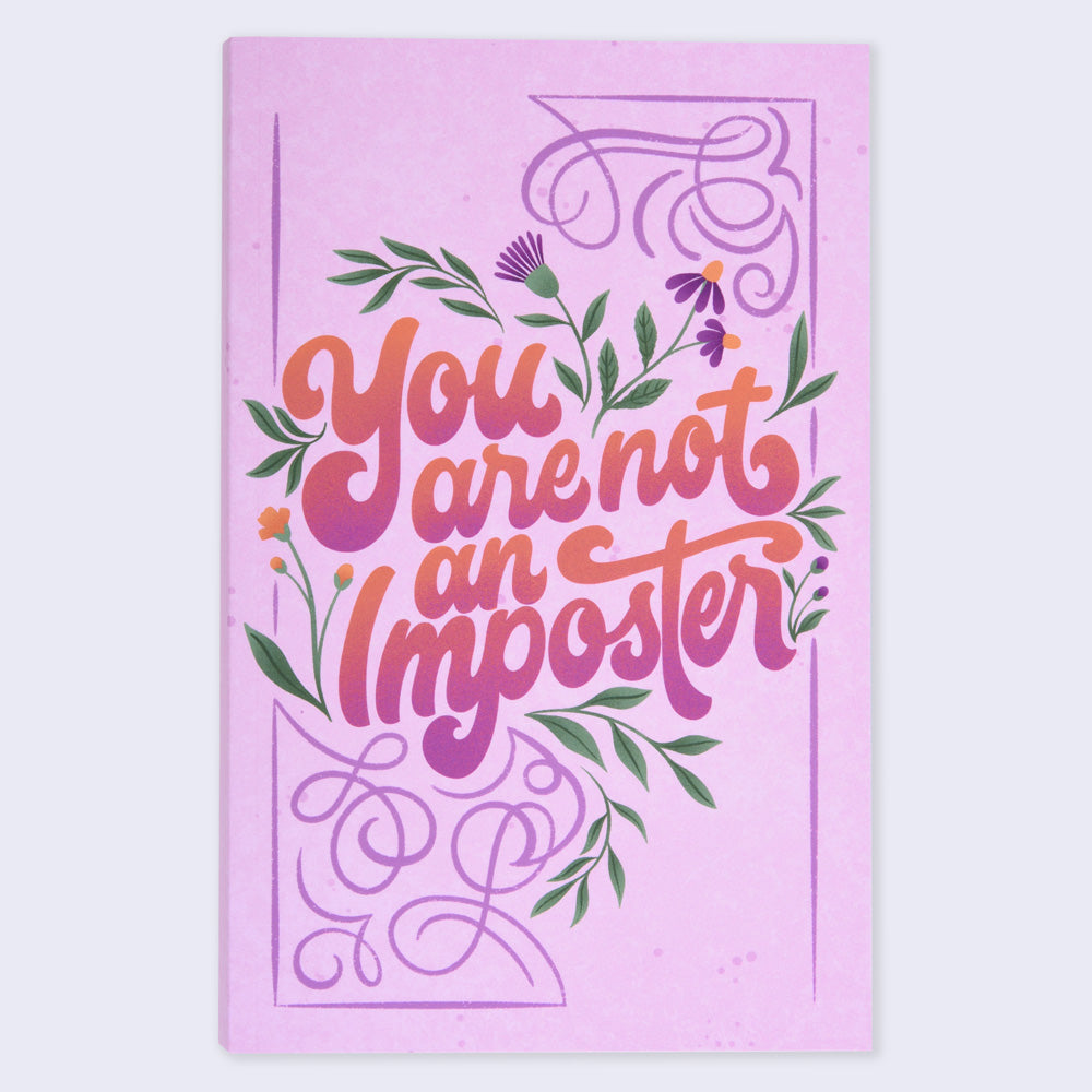 A flat lay view of a pink notebook with a floral design and the text &