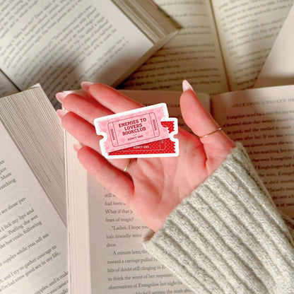 Hand holding a red and white card with text over open books
