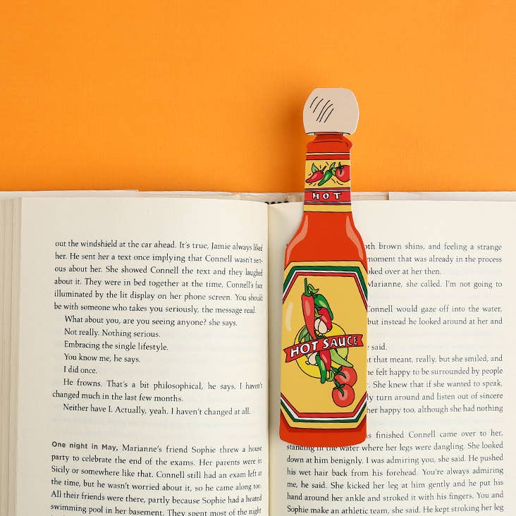 Hot sauce bottle-shaped bookmark on an open book with an orange background