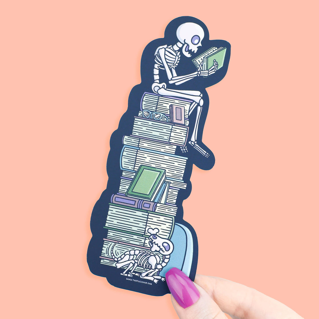 Sticker of a skeleton reading a book on a stack of books with a pink background