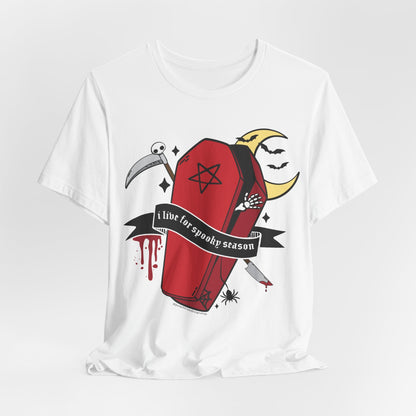 A white short-sleeve crewneck t-shirt featuring a gothic-themed graphic print of a red coffin with a black pentagram, a scythe, a black banner reading &
