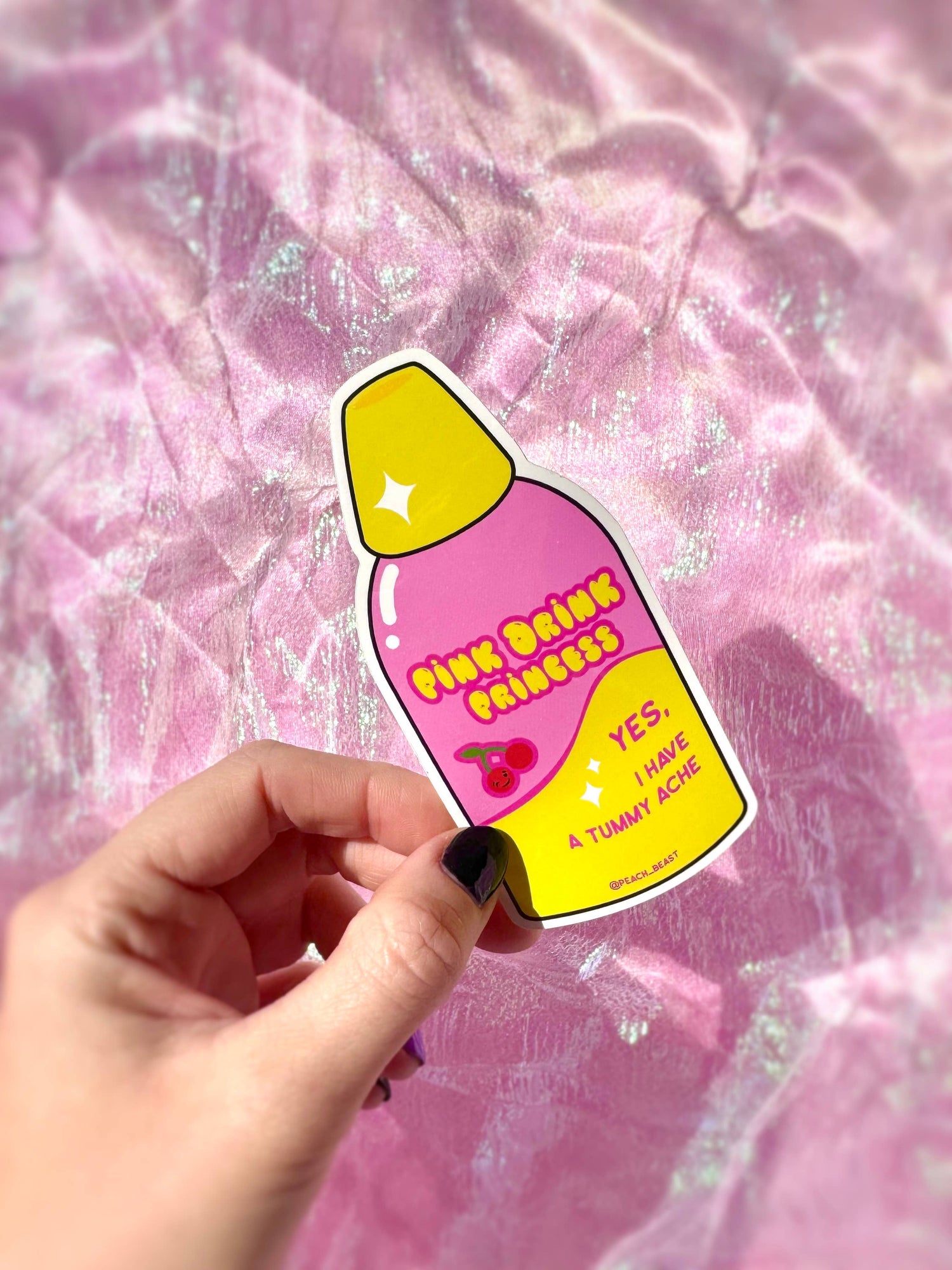 Sticker with pink drink princess design held by a hand against a pink textured background
