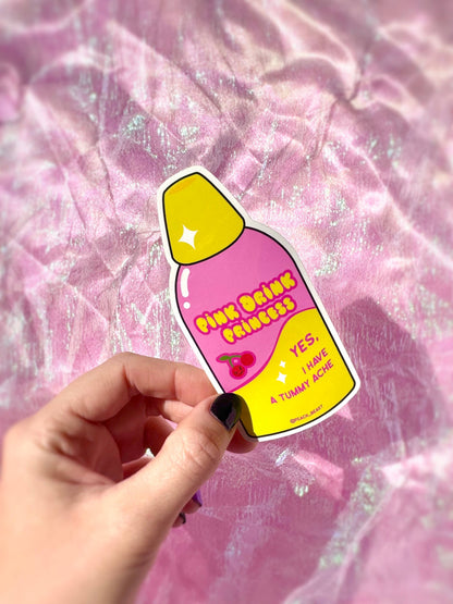 Sticker with pink drink princess design held by a hand against a pink textured background