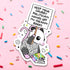 Sticker of an opossum holding a sign with text on a pink background with colorful sprinkles.