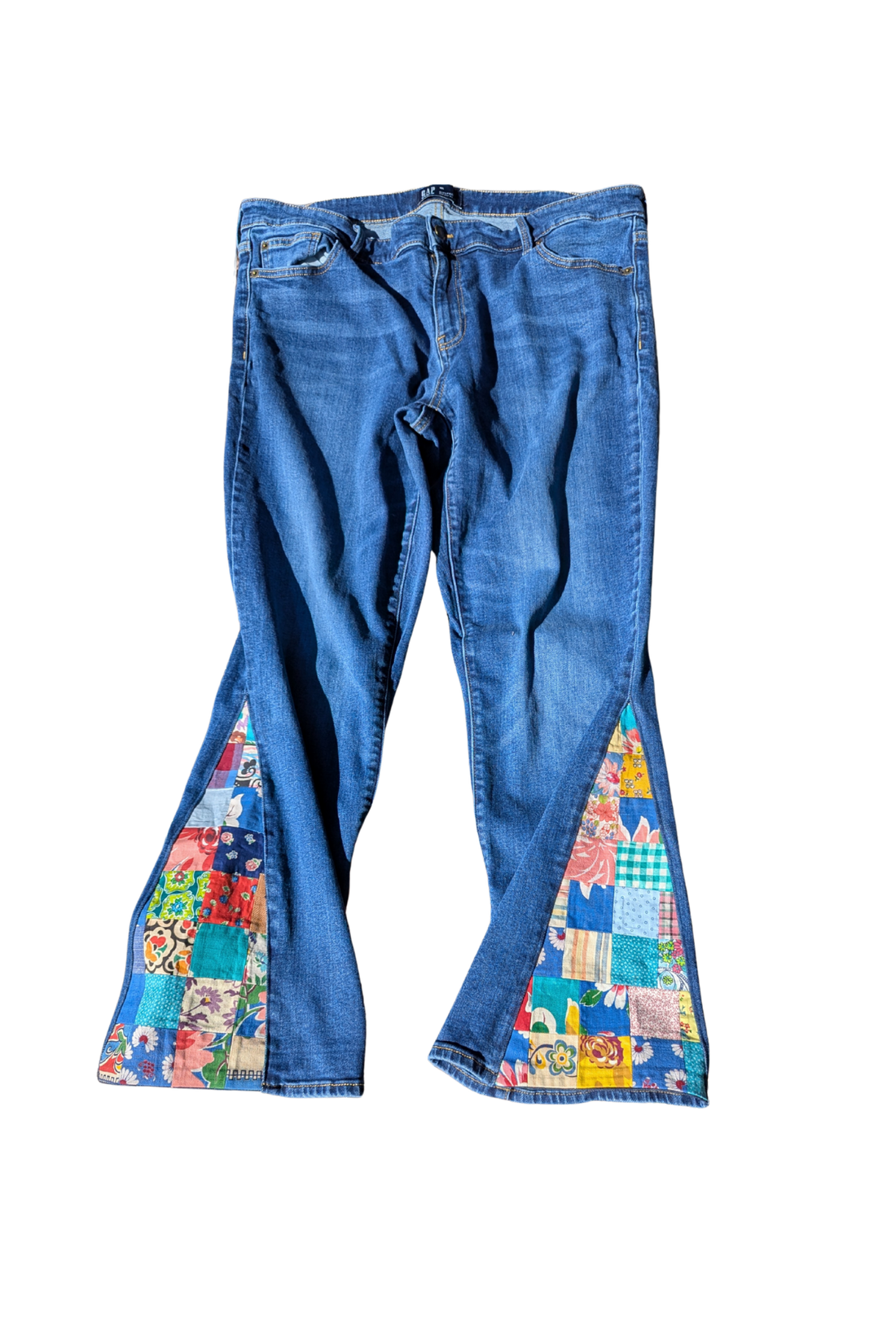 Blue jeans with colorful patchwork design on a white background