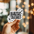 Hand holding a sticker with &