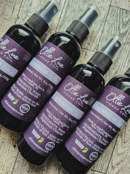 Row of Ollie Lue Soap Co. magnesium spray bottles on a gray background