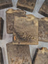 Several handmade rectangular bars of soap in a dark brown and beige marbled pattern, with the brand name &