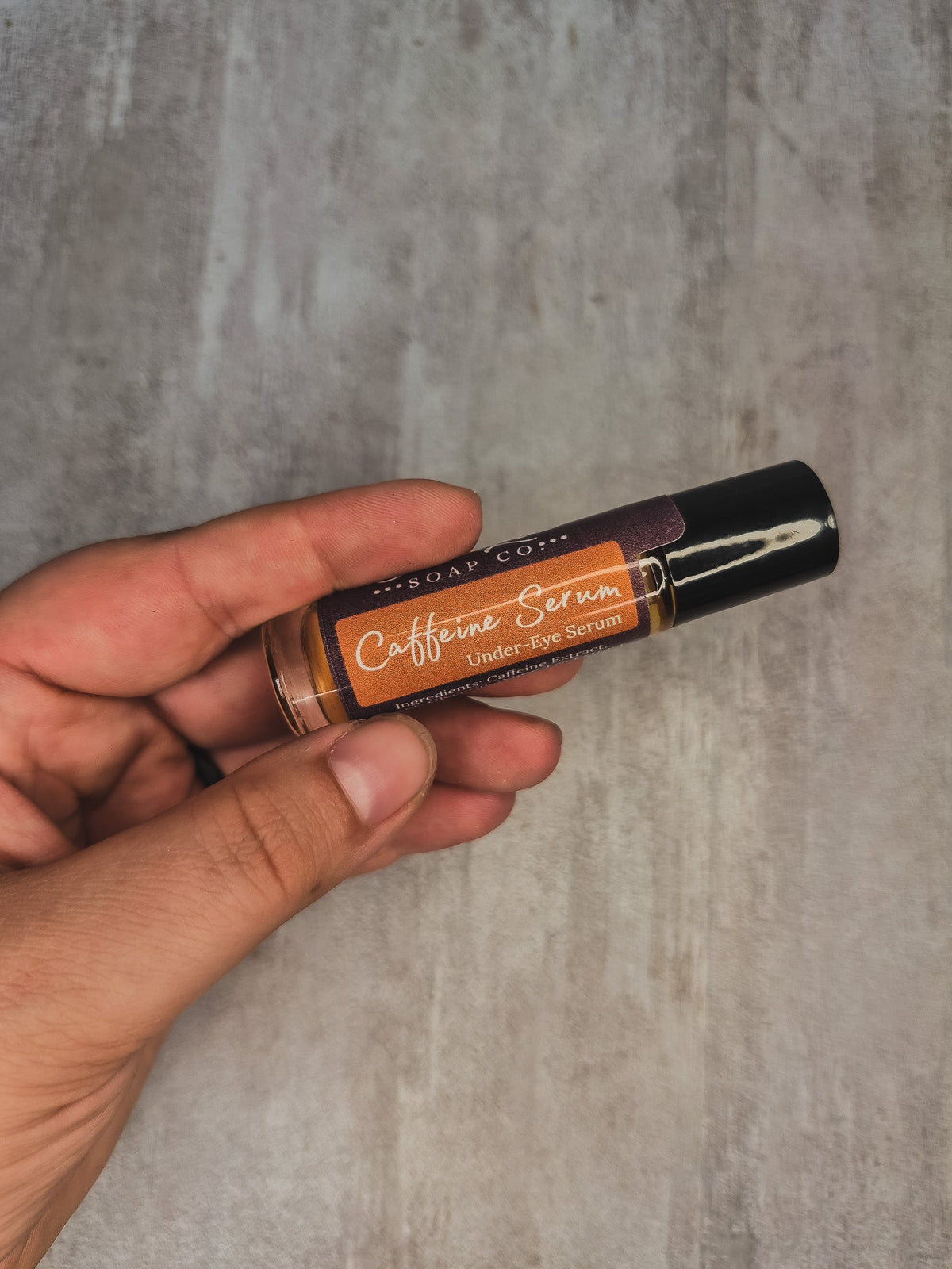 A hand holding a small cosmetic tube labeled &