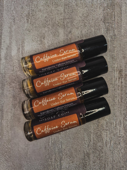 Four under-eye serum rollerball bottles from Soap Co. arranged diagonally on a textured gray background.