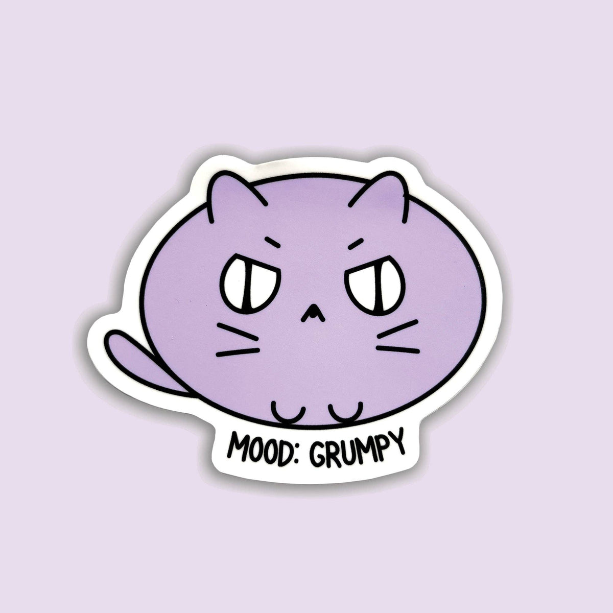 A die-cut sticker featuring a cartoon purple cat with a grumpy expression and the text &