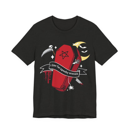 A black short-sleeve crewneck t-shirt featuring a gothic Halloween graphic of a red coffin with a pentagram, a scythe, a spider, a bat, and a banner that reads &
