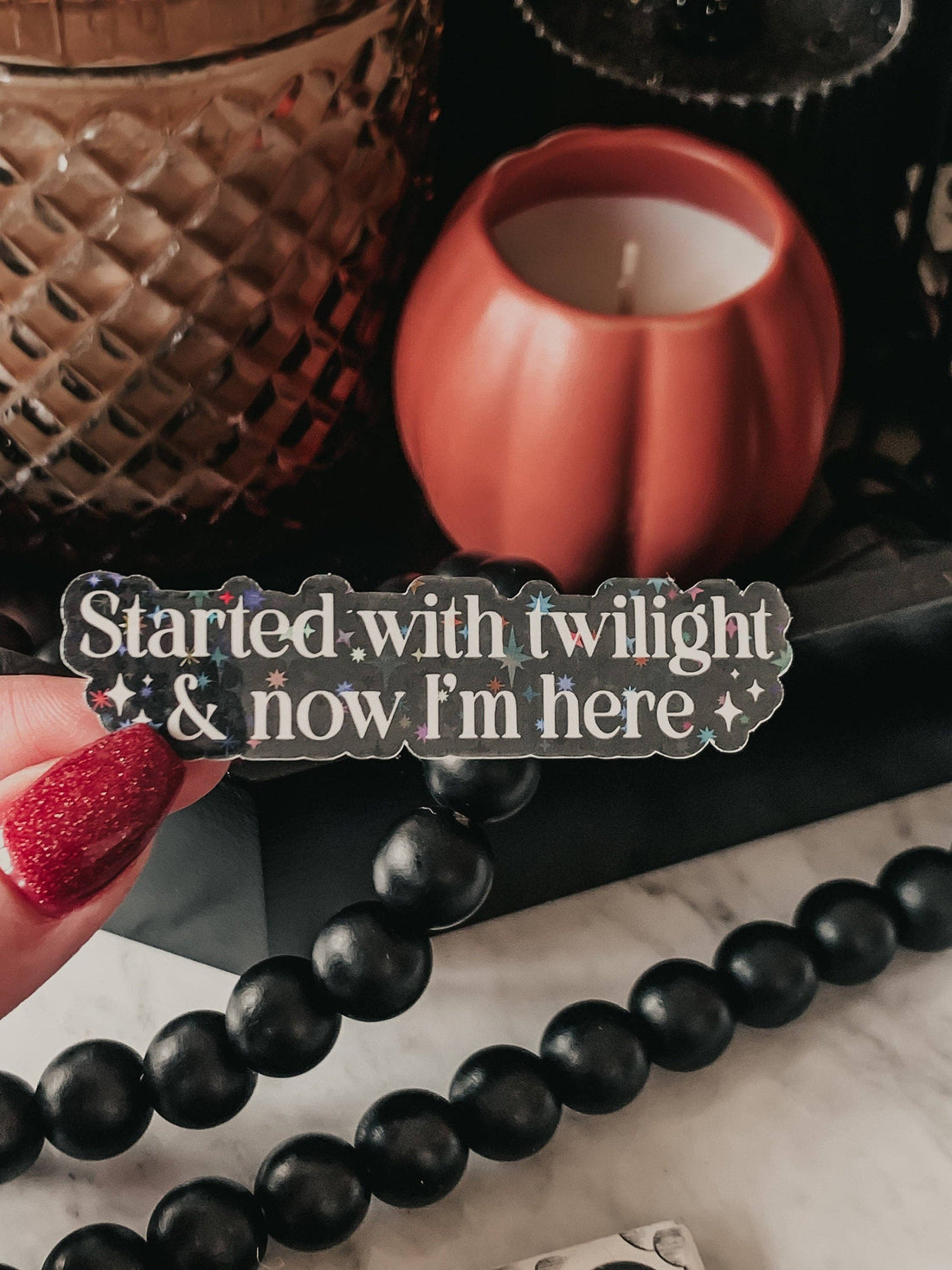 Black beaded bracelet with a pumpkin-shaped candle and textured container in the background.
