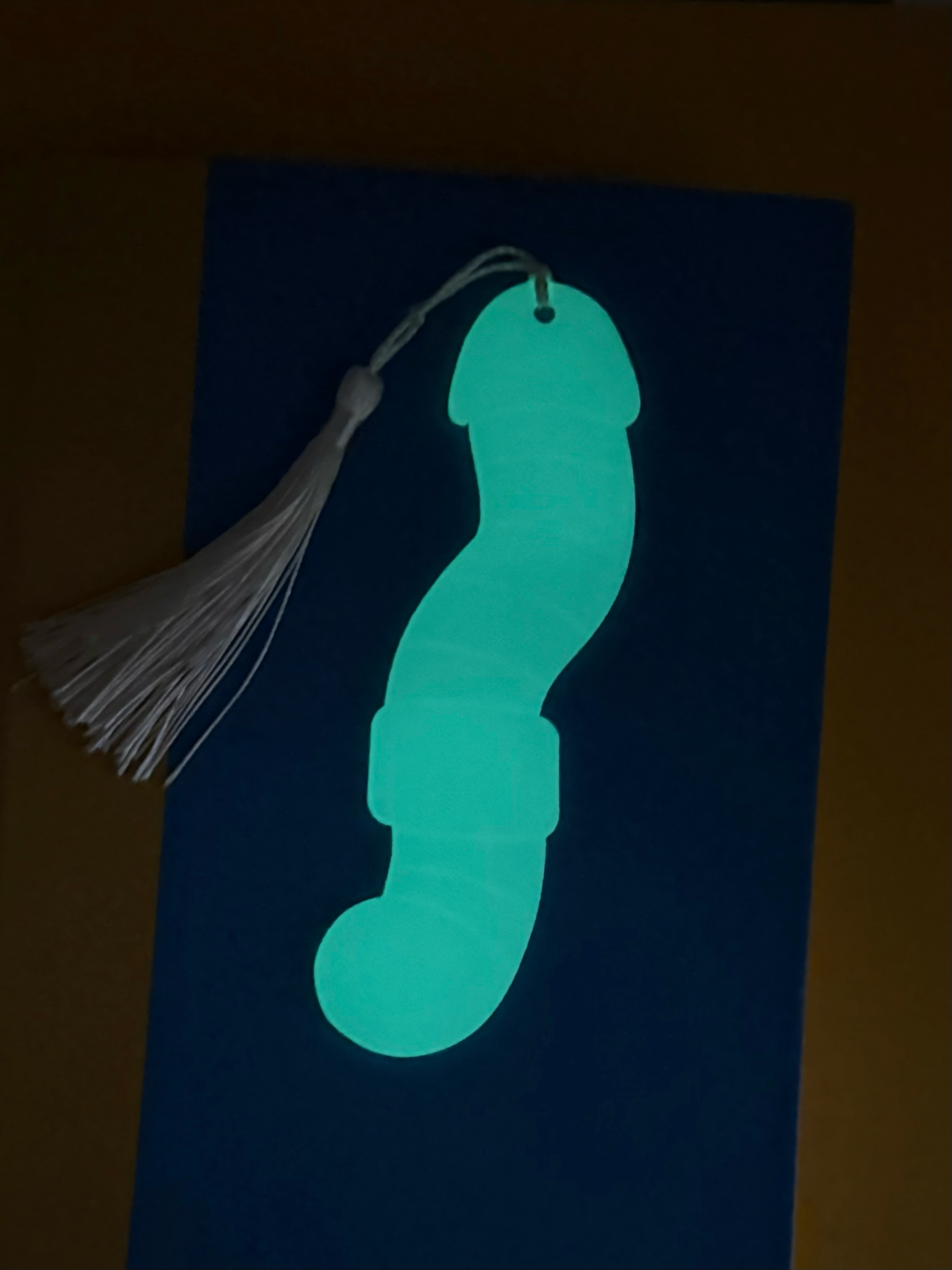 Glowing worm-shaped object with a tassel on a dark background