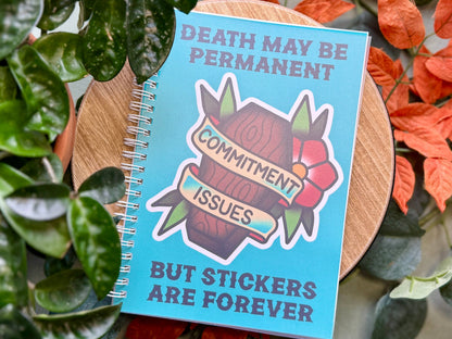 Notebook with a sticker on it, surrounded by plants