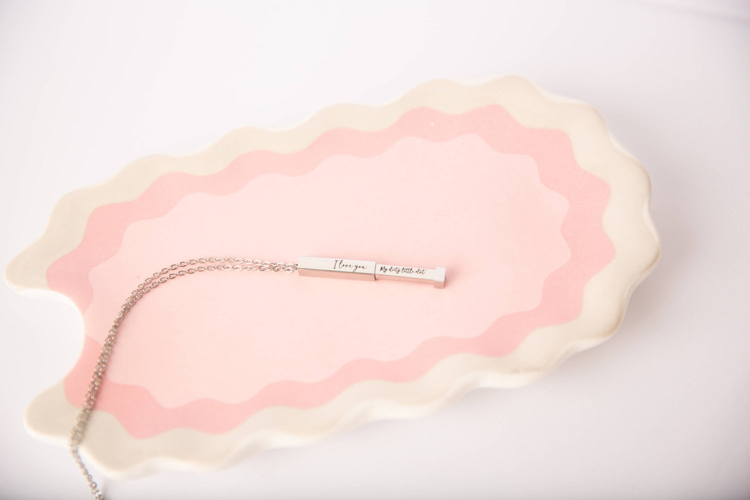 Necklace with a pendant on a pink and beige textured surface